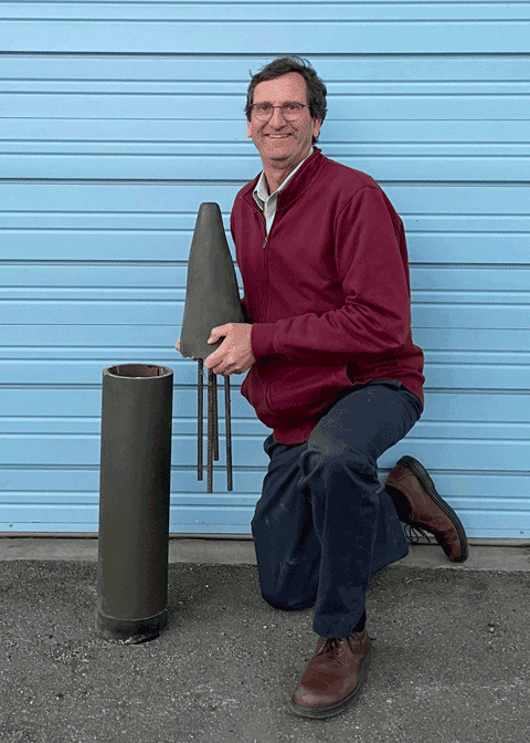 man holding a mock up of military ammunition with a wireless sensor in it