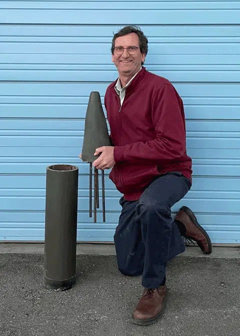 man holding a mock up of military ammunition with a wireless sensor in it