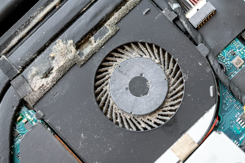 Close up detail view of disassembled laptop pc motherboatd with dirty dust chip gpu cooling fan part. Fixing computer overheating. Professional Tech and electronics service fix repair maintenance