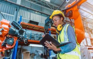 Engineer smart woman worker working programing robotic welding machine. Black teen girl work in advance modern factory.